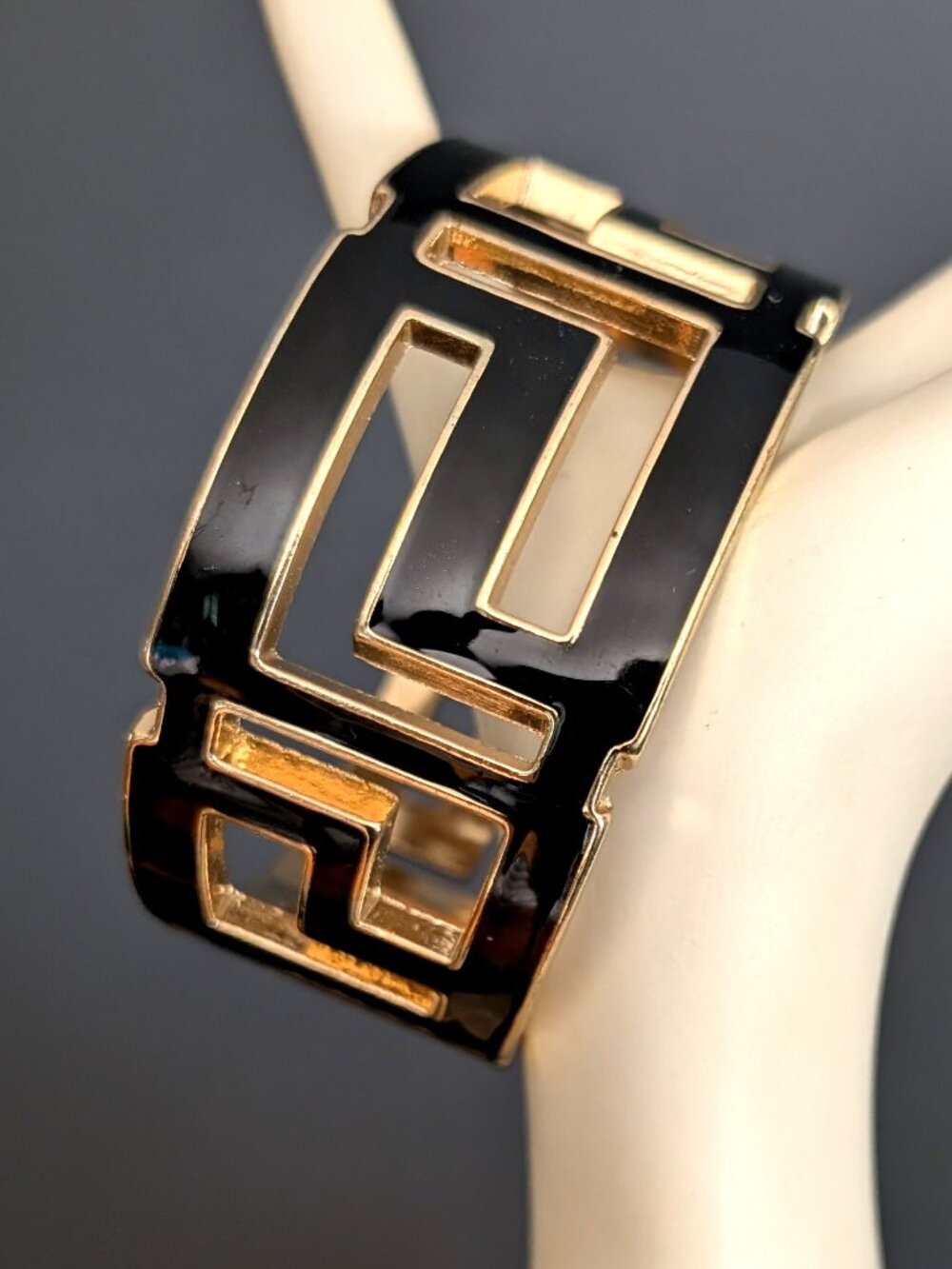 Black enamel gold tone hinged closure bracelet